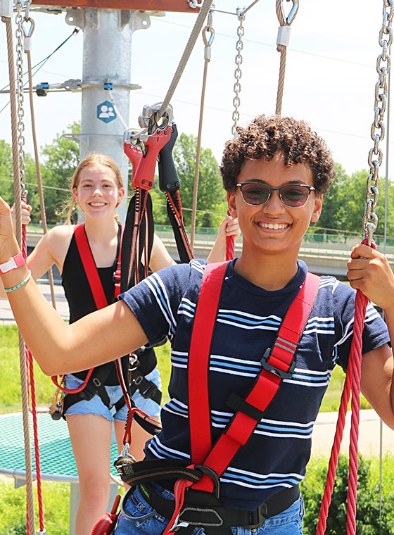 teenage boy and girl having a blast as they play on the aerial ropes course