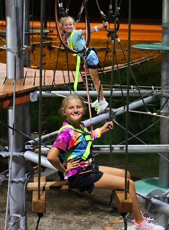 2 young girl playing on adventure tower at an event