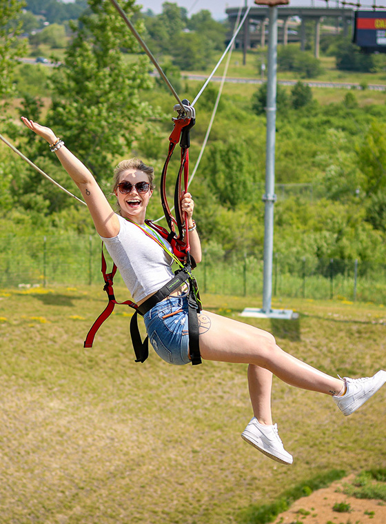 Young female soaring with arms out on the ziplines